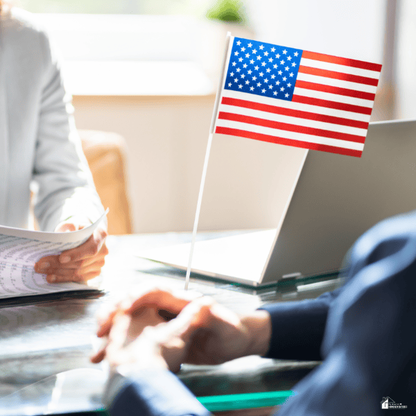 Two people review paperwork beside an American flag and laptop, illustrating a legal consultation about deportation cases.