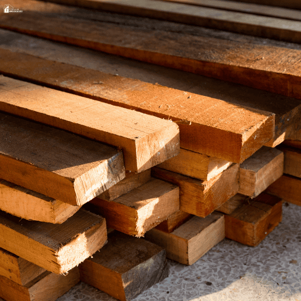 Stacked timber boards show the weathered surfaces, varied tones, and rough edges used to create reclaimed wood flooring.