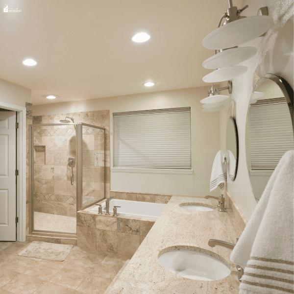 A bathroom remodel features a double-sink vanity, oval mirrors, a built-in bathtub, and a glass-enclosed tiled shower.