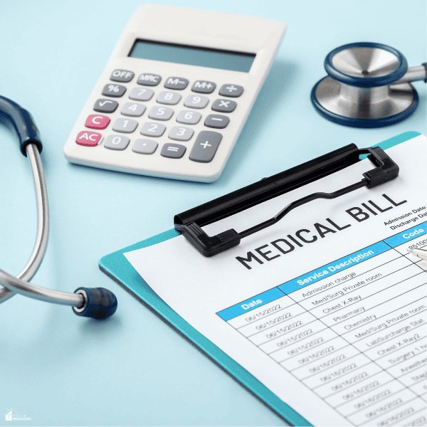 A calculator and stethoscope beside a healthcare invoice illustrate managing unexpected medical expenses.
