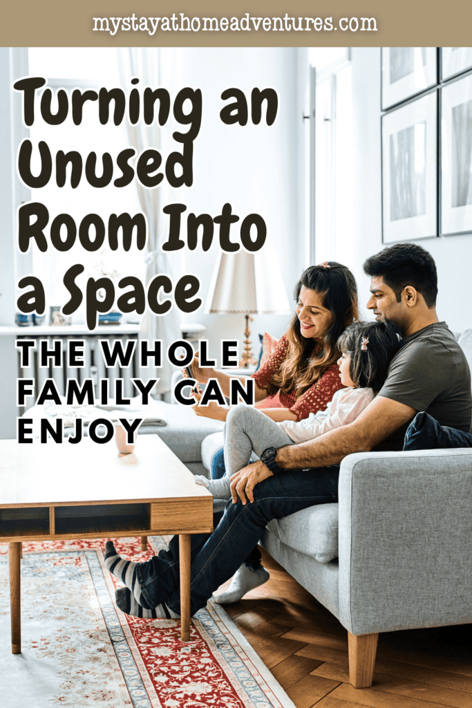Parents sit with their daughter on a gray sofa beside a wooden coffee table, showing inspiration for converting an unused room into a space for spending time together.