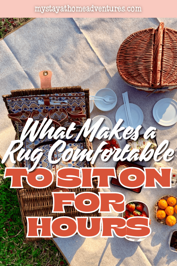 Wicker baskets, dishes, sandwiches, and fruit sit on a woven picnic rug that creates a comfortable gathering space on grass.