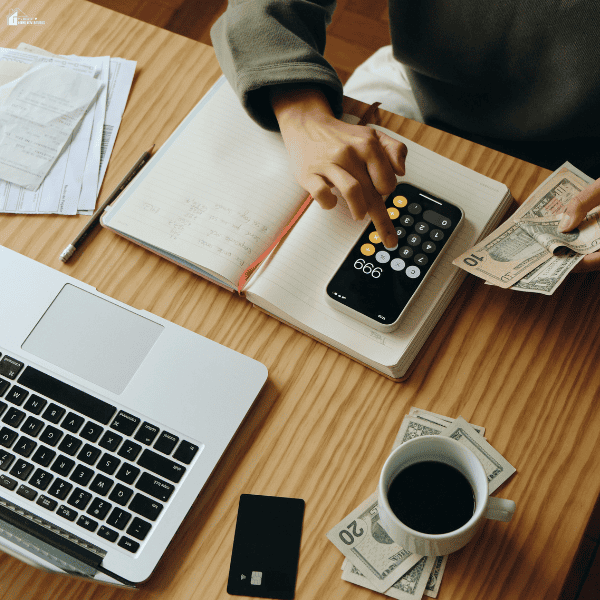 Person counts cash using receipts, a notebook, and a phone calculator to track essential expenses after separation.